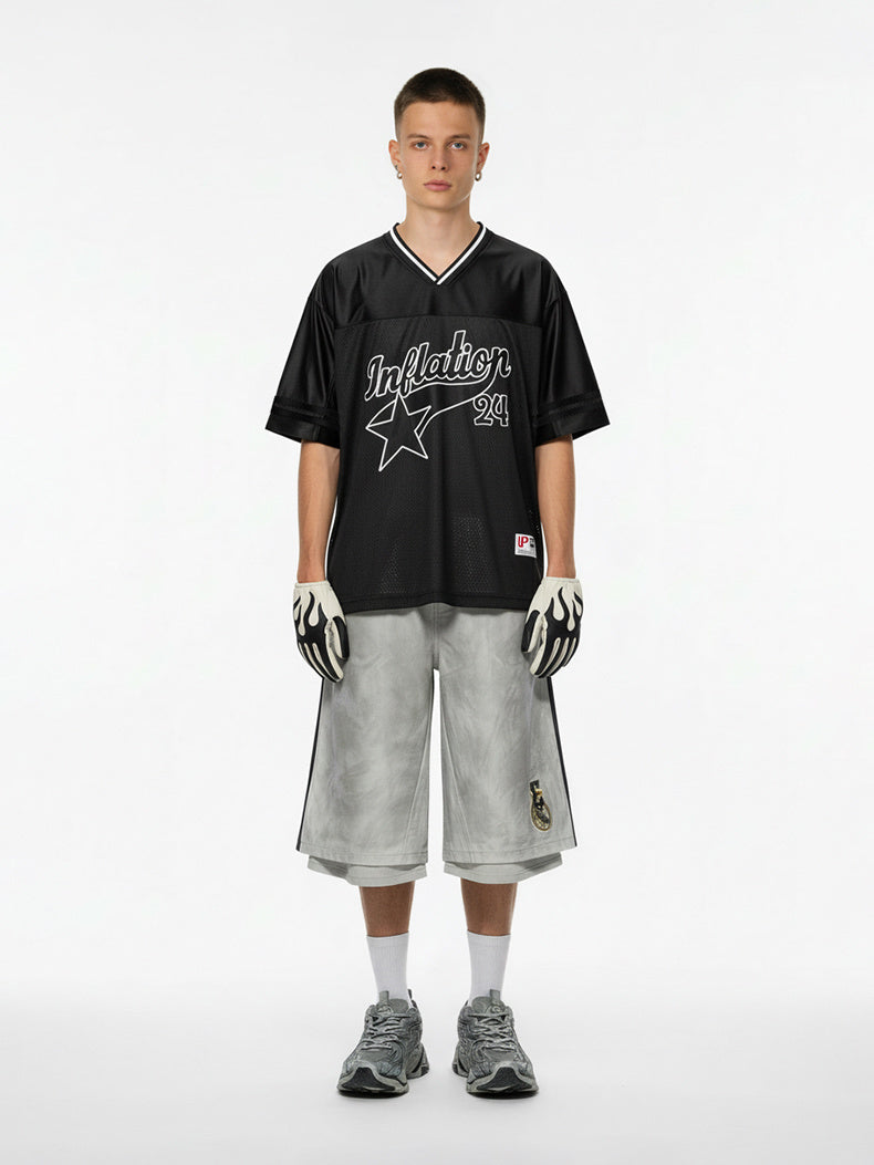 Black mesh varsity jersey with star graphic and V-neck styling on a model, paired with gray shorts and gloves