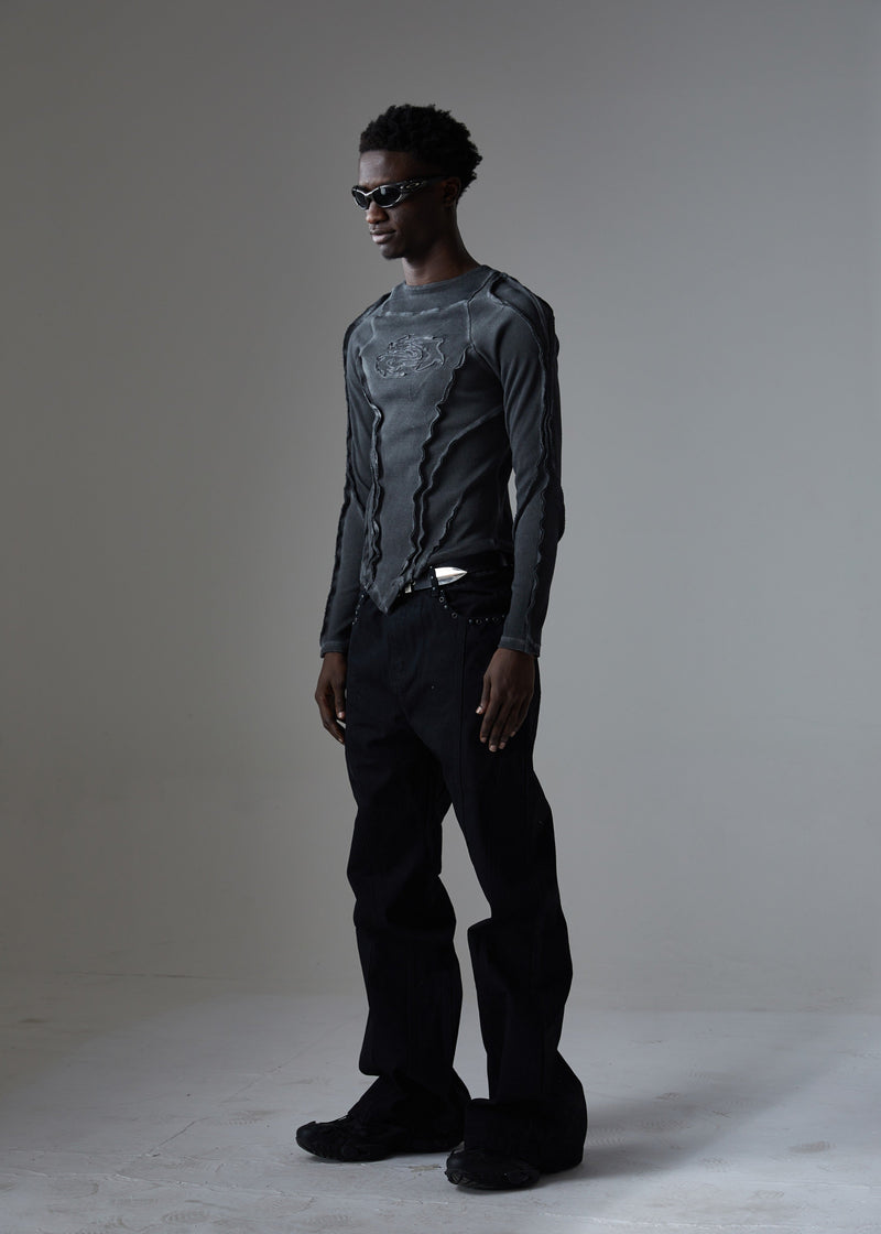 Side view of black wide-leg jeans with studded pocket trim and layered top