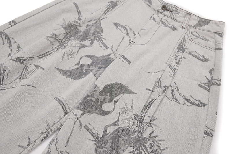 Diagonal close-up of the upper front of gray wide-leg jeans with ink-wash print