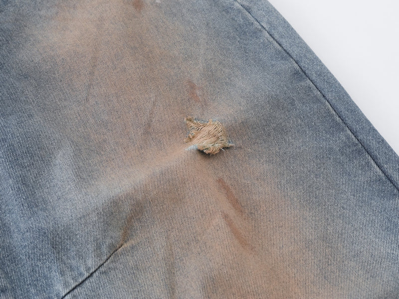 Close-up of a frayed rip on the faded denim leg