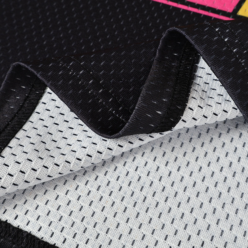 Close-up of black and white mesh football jersey fabric with pink accents and textured athletic knit detailing