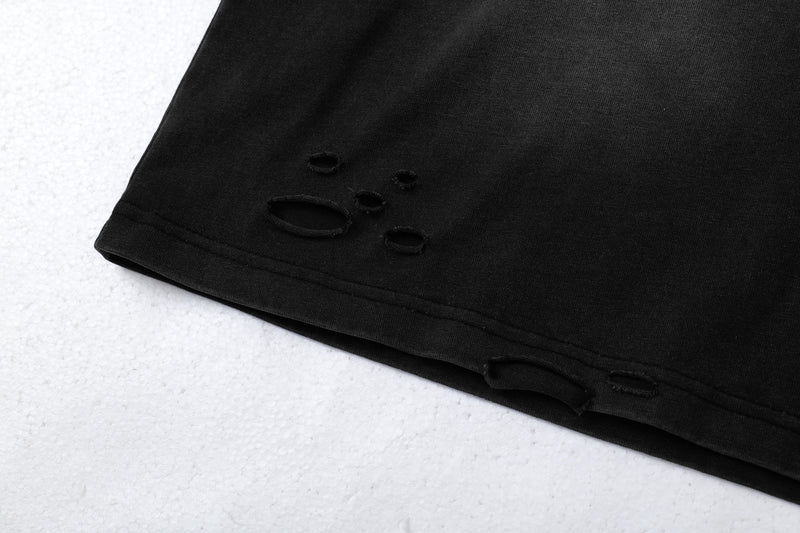 Close-up of black hem with distressed holes near the side seam