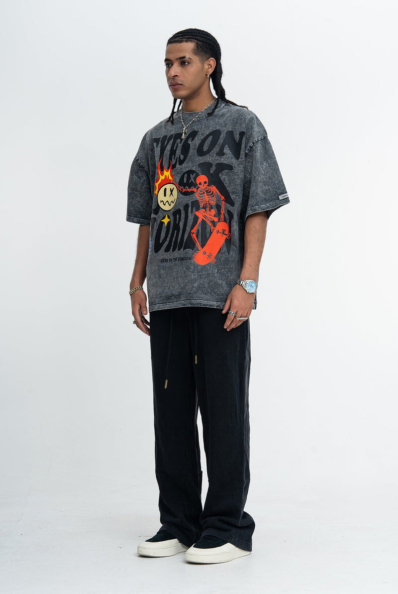 Model wearing a vintage-wash black graphic tee with bold skeleton skateboard print and oversized fit