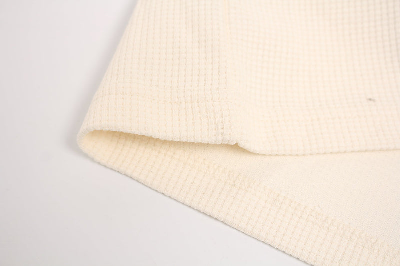 Close-up of cream ribbed fabric hem on a distressed streetwear dog graphic T-shirt