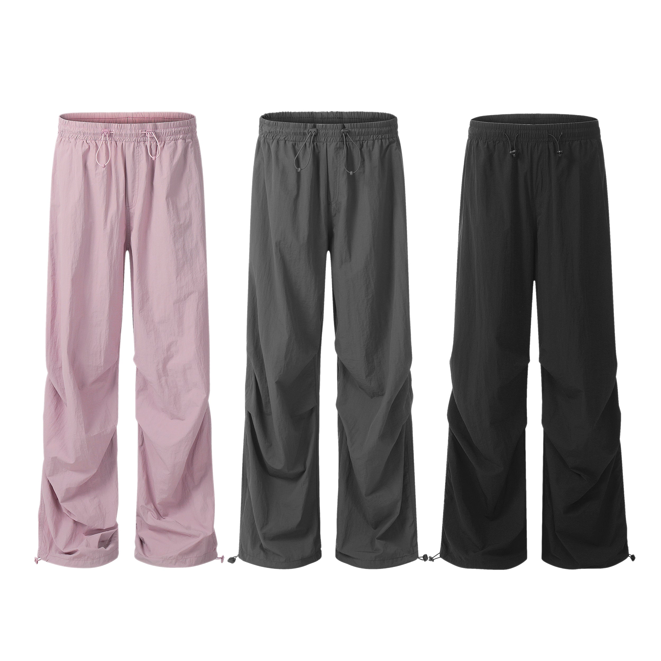 Three lightweight nylon drawstring parachute pants displayed side by side in pink, charcoal grey, and black with elastic wais