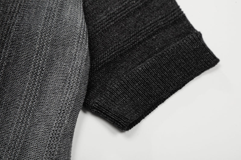 Close-up of black and gray open-knit polo sleeves with subtle gradient stripe texture and relaxed fit fabric detail