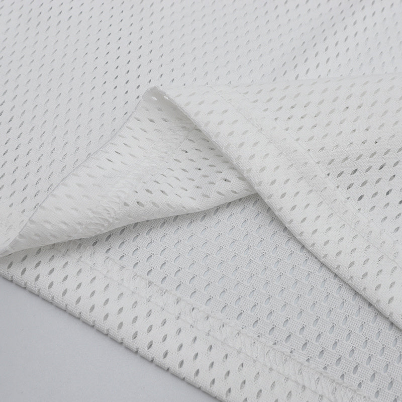 Close-up of white breathable mesh football jersey fabric with textured perforated knit