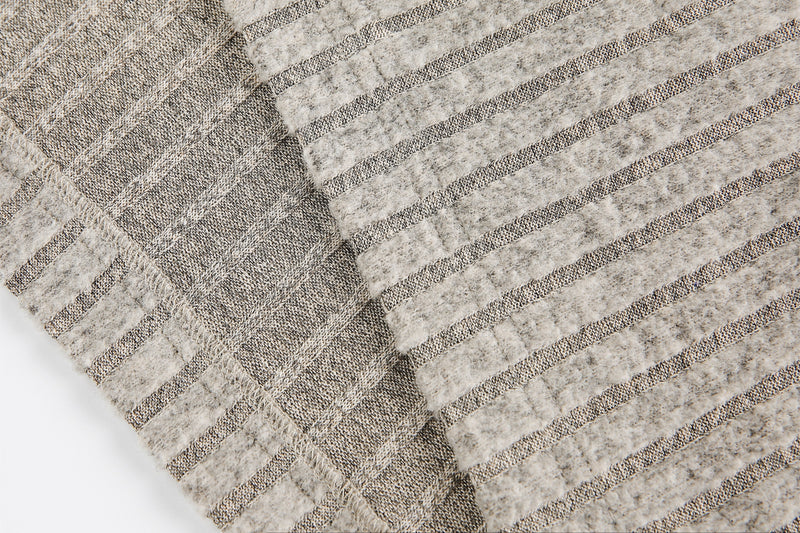 Close-up of beige ribbed knit sleeve fabric and textured stripe detail