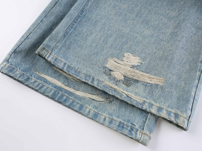 Lower leg detail of light blue wide-leg jeans with distressed frayed patches