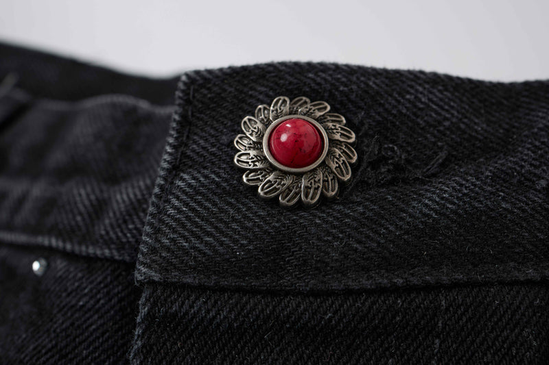 Close-up of red-and-silver decorative button on black denim