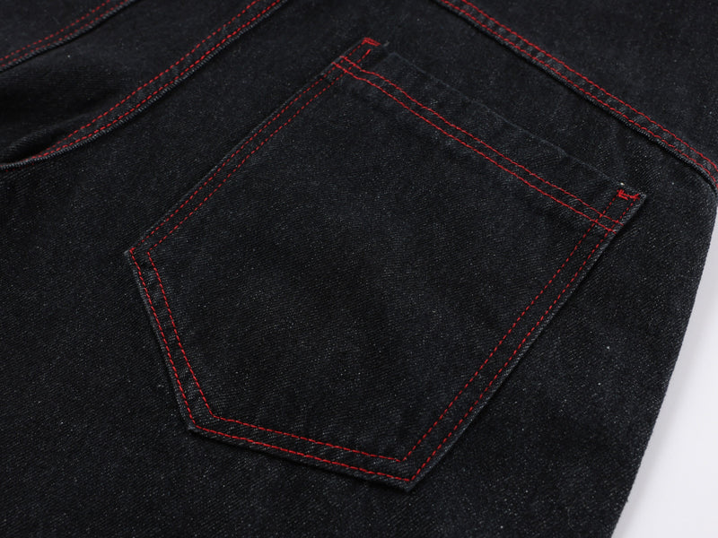 Close-up of back pocket on black denim pants with red contrast stitching