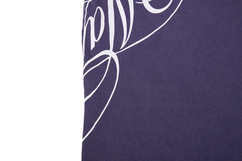 Close-up of a washed purple streetwear tee with oversized white graphic lettering on soft cotton fabric
