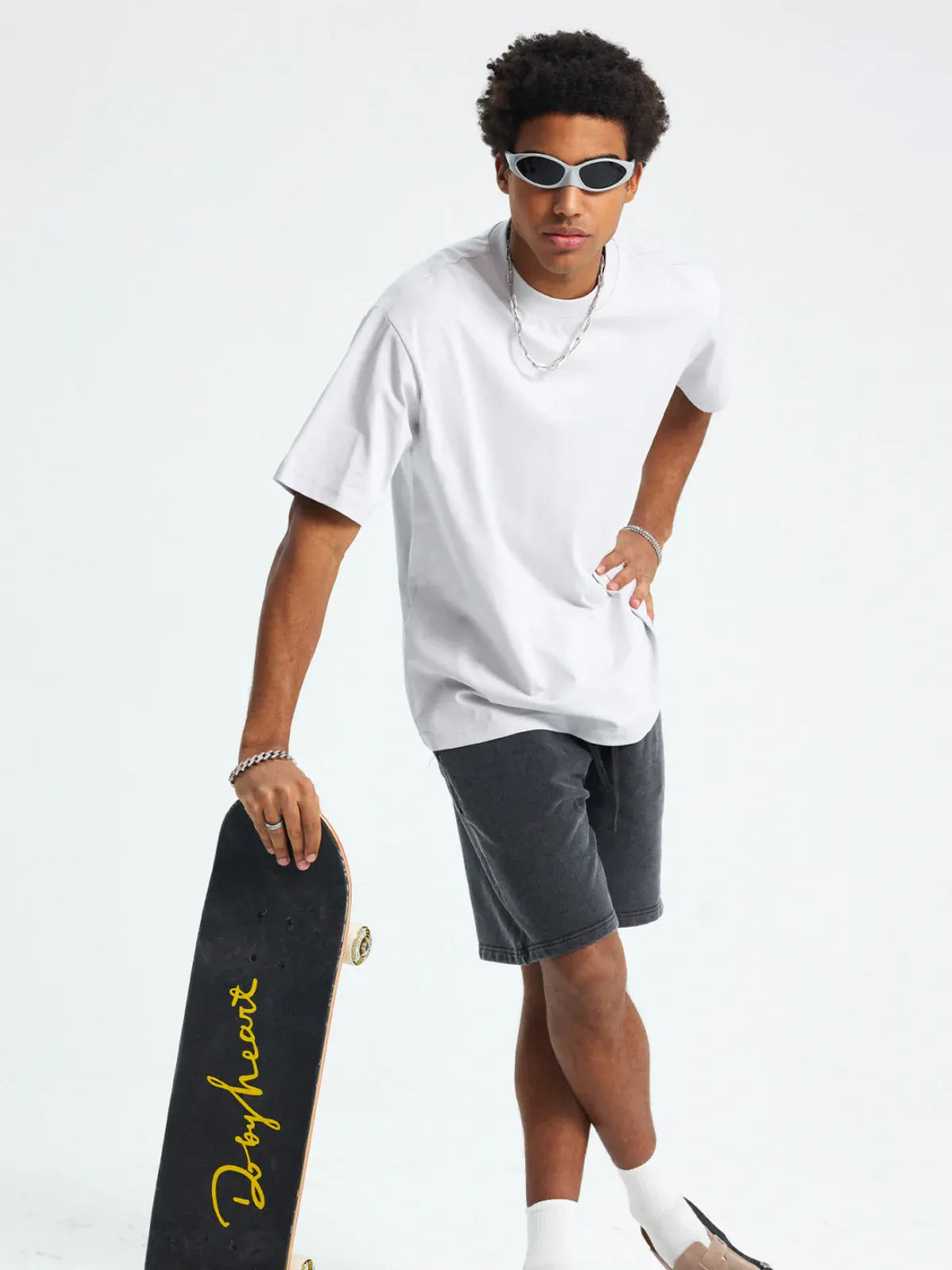 Wearing sunglasses, black shorts, white socks, and holding a Dog Heart skateboard, a person stands against a plain white background in a Custom Anime Character White T-Shirt - Personalized 230GSM 100% Cotton Tee.