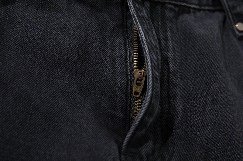 Close-up of the front zipper on washed black denim jeans