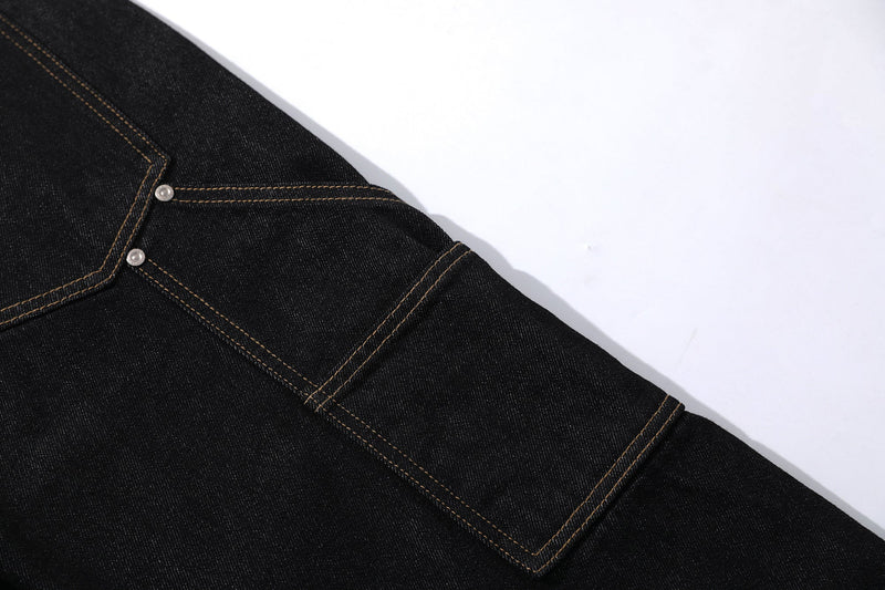 Close-up of black cargo jean leg with angled seam and topstitching