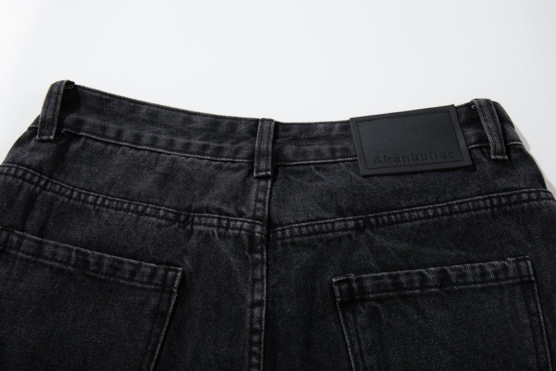 Close-up of the back waistband on black denim jeans with belt loops and branded patch