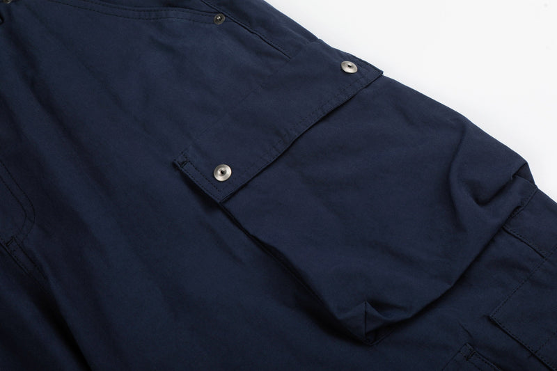Close-up of navy cargo pants side pocket flap with snap button and stitching
