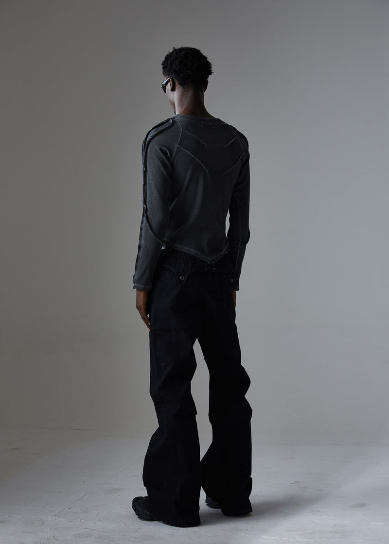 Back three-quarter view of black studded wide-leg jeans and graphic long-sleeve top