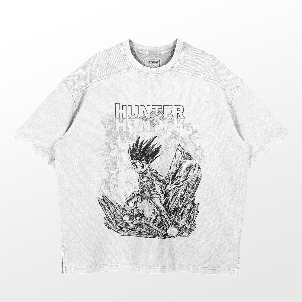 The Hunter x Hunter Gon Freecss Washed Vintage T-Shirt is a gray, short-sleeved tee featuring an anime character illustration on rocks, with &quot;HUNTER&quot; text above. Made of 260 GSM high-quality cotton, this streetwear offers a casual fit with visible stitching.