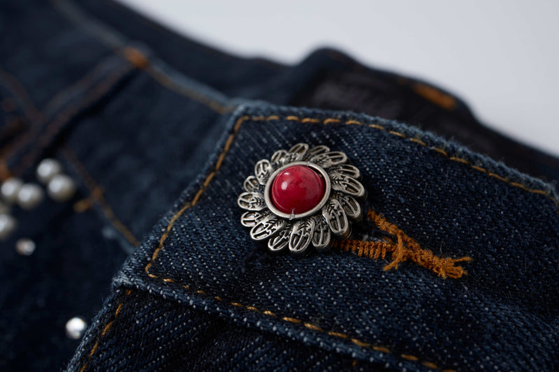 Close-up of front pocket button with red stone on black denim