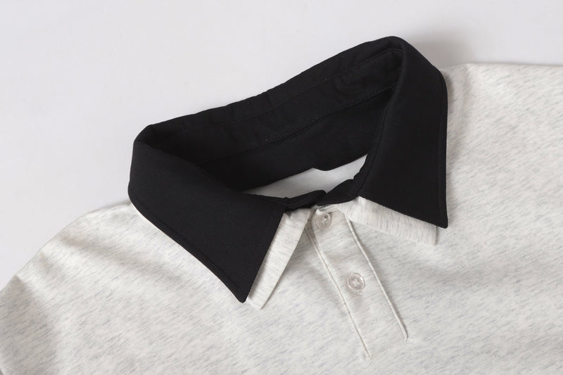 Close-up of black pointed polo collar over light gray heathered shirt with partial button placket