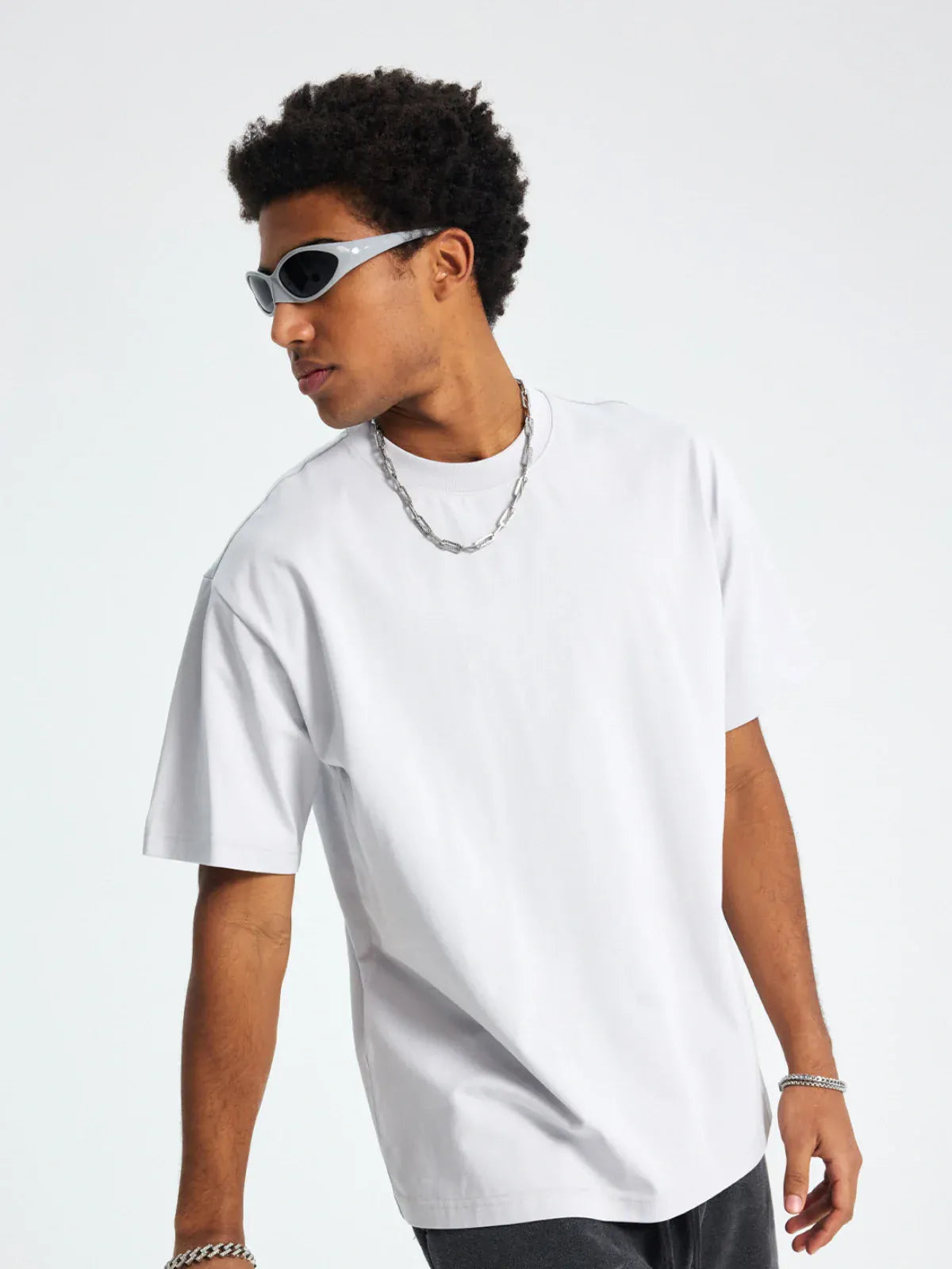 A man in a Custom Anime Character White T-Shirt—Personalized 230GSM 100% Cotton Tee—silver chain, bracelets, and dark sunglasses stands against a plain light background, looking to his left.