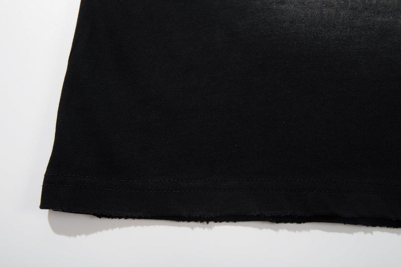 Black washed graphic T-shirt hem with raw edge and visible double stitching on soft cotton fabric