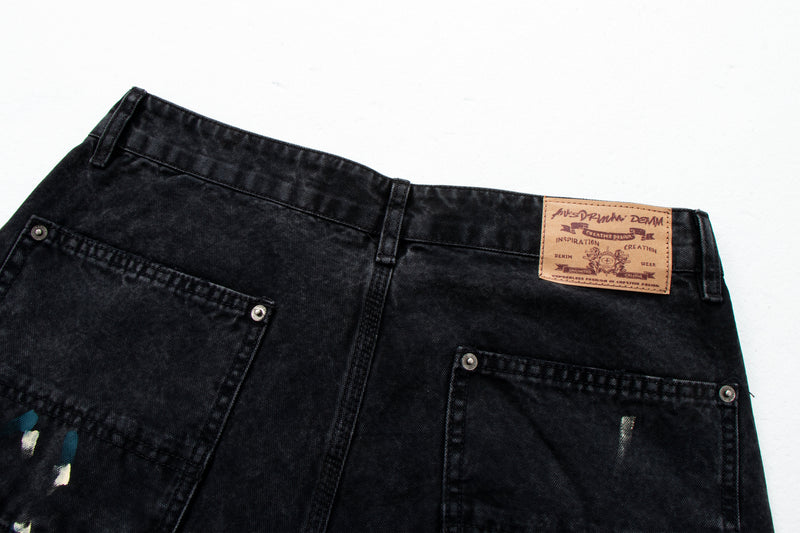 Close-up of back waistband on black denim pants with logo patch and rear pockets