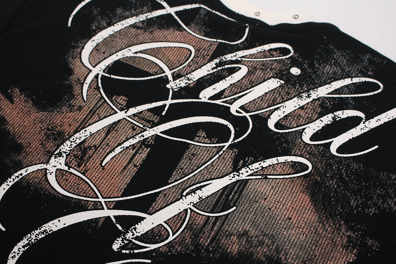 Close-up of a black graphic tee with distressed white gothic script and cross-style lettering print on the chest