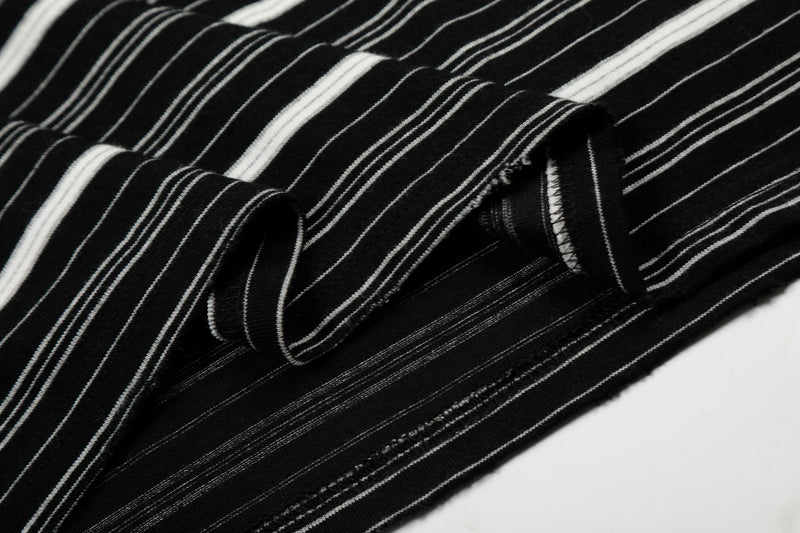 Close-up of black striped sleeve with distressed hole and ribbed cuff