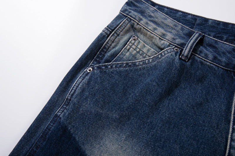 Angled close-up of front pocket and waistband on dark blue faded denim jeans