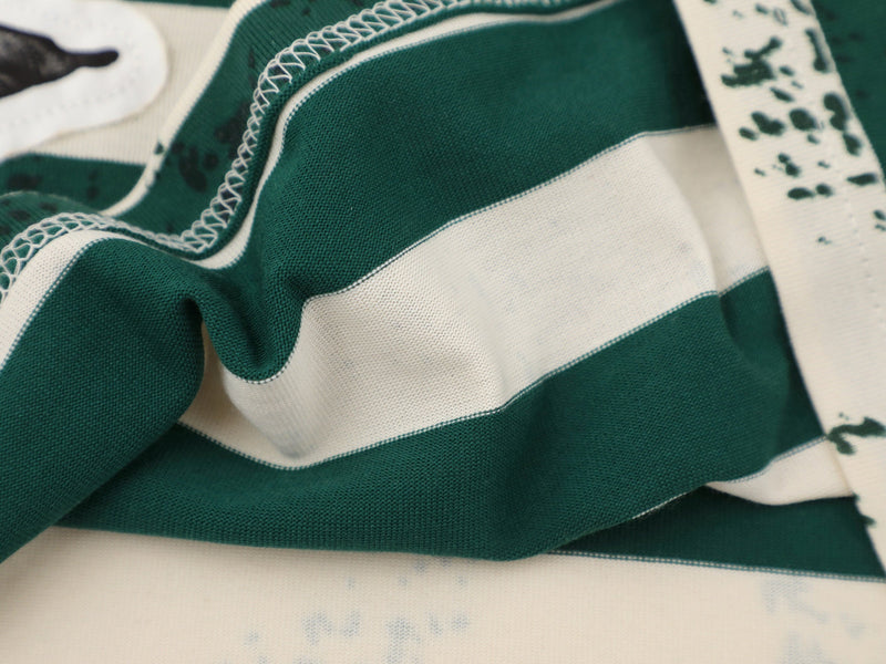 Close-up of green striped tee fabric with folded seam and overlock stitching