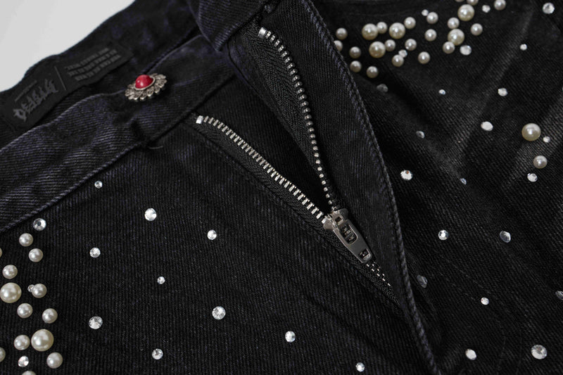 Close-up of black denim waistband zipper and pearl stud detail