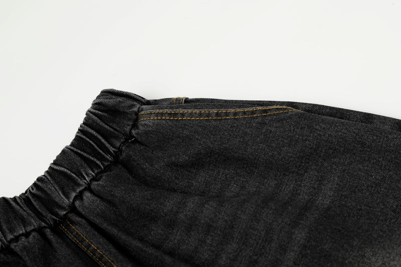 Close-up of elastic waistband and top seam on black washed denim pants