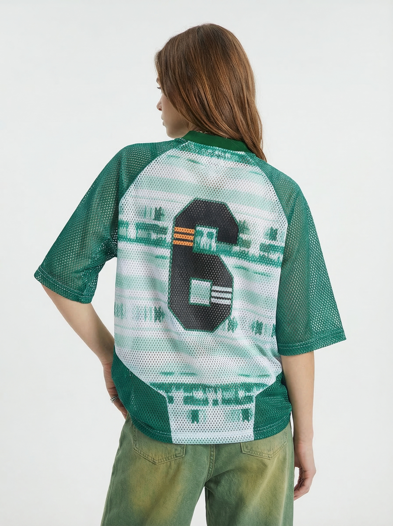Green mesh varsity jersey T-shirt with oversized black number 6 on the back, worn with faded green pants