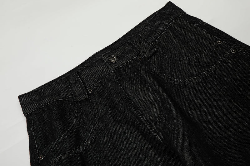 Close-up of black denim waistband with belt loops, button closure, and curved front pocket seam