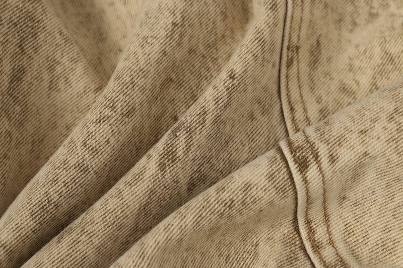 Close-up of beige denim fabric showing faded wash and diagonal twill texture