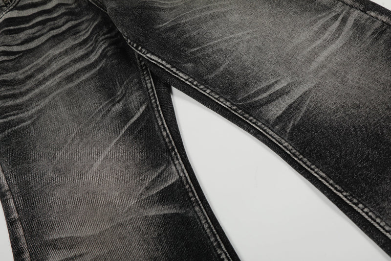 Close-up of black washed denim legs showing vertical fading and stitched seams