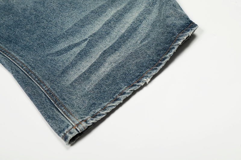 Close-up of jeans hem with frayed edge and faded blue denim