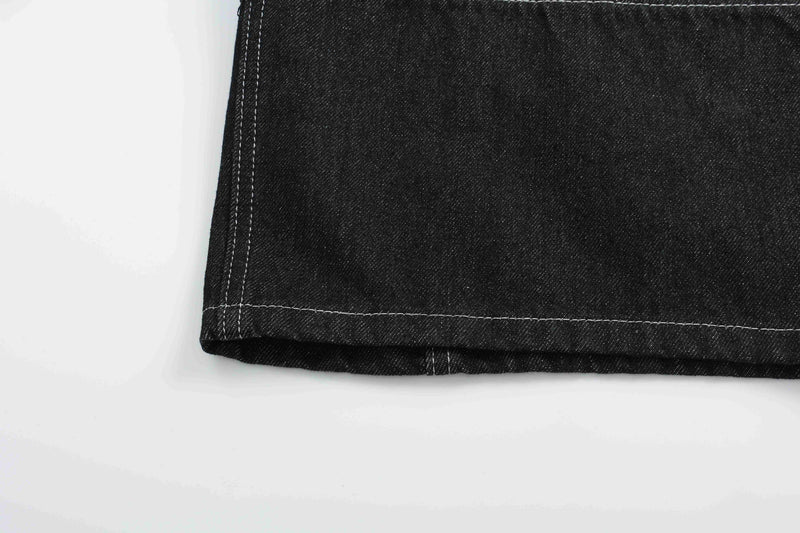 Bottom hem of black denim shorts with straight white stitching