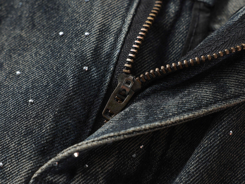 Close-up of metal zipper on black denim pants with scattered rhinestones