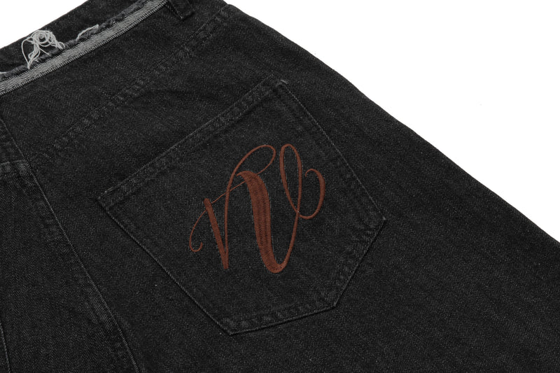 Close-up of back pocket on black denim shorts with red embroidered design
