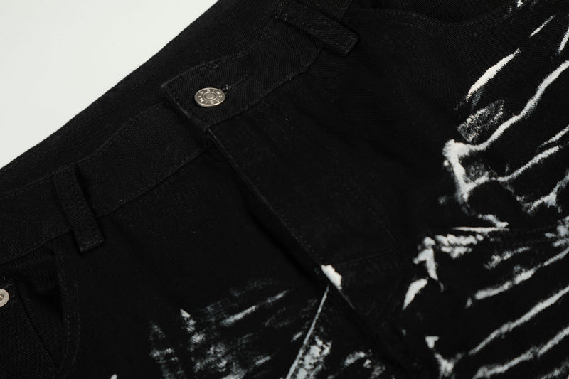 Close-up of black denim waistband, button, and white brush-stroke graphic detail