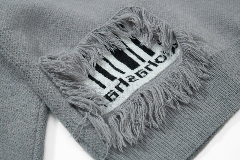 Gray knit sweater close-up of front patch graphic trimmed with long fringe