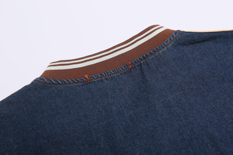 Close-up of a vintage blue denim jersey tee with brown and white striped ribbed collar and orange contrast stitching