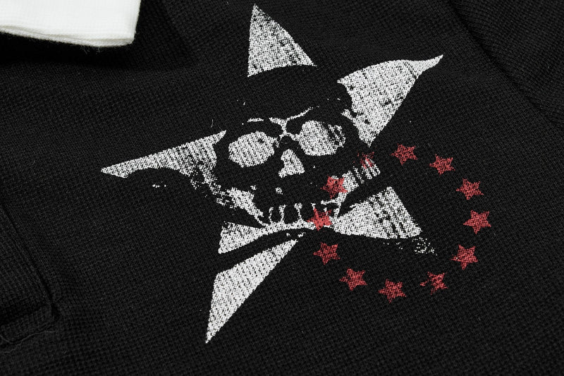 Close-up of black polo shirt with a distressed skull graphic, white star shapes, and red stars on textured fabric