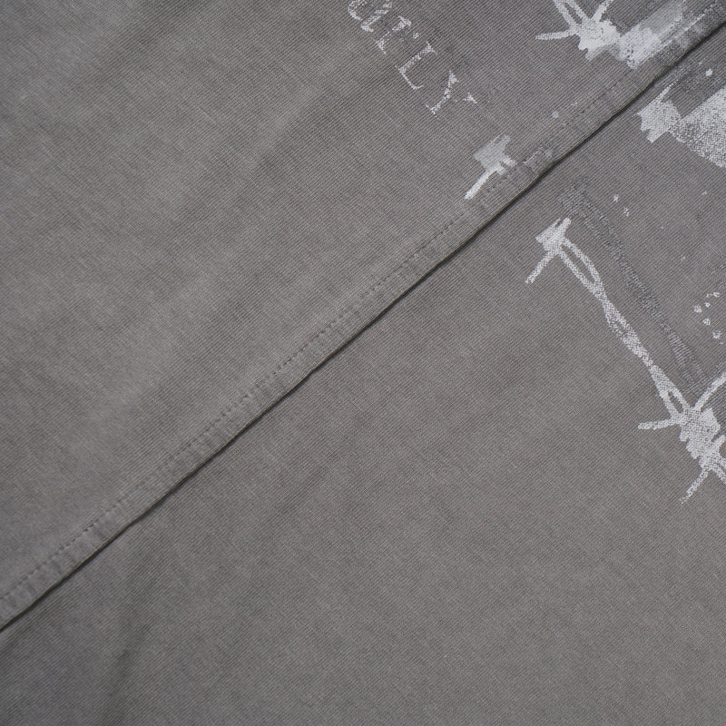 Washed grey tee close-up showing printed graphic edges and diagonal seam detail