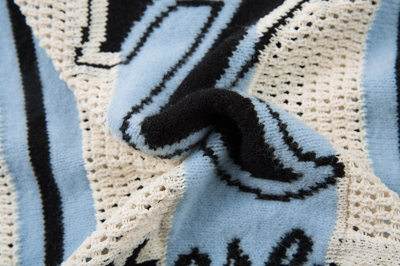 Close-up of lace-up V-neck detail on light blue and cream knit sweater
