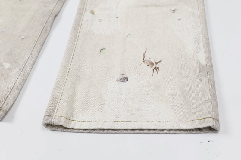 Close-up of lower leg on washed botanical print jeans with small shell and crab-like graphics
