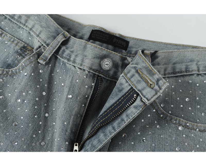 Front waist of light-wash jeans with button closure and partially open zipper fly